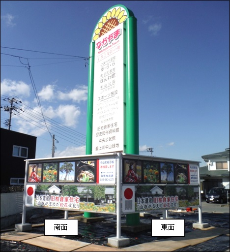 四角いコンクリートを土台にしたポールで掲示枠を建てて、そこに風景や食べ物などの写真が掲示されている南面と東面が撮影された催事等掲示枠の写真