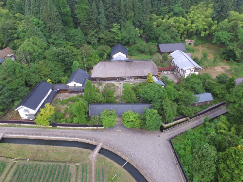 緑豊かな木々を背景に、緑に囲まれた大規模住宅の旧柏倉家住宅を上空から撮影した写真