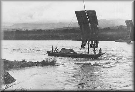 4名が乗った1艘の艜船が荷物を載せて最上川を進んでいる様子の白黒写真
