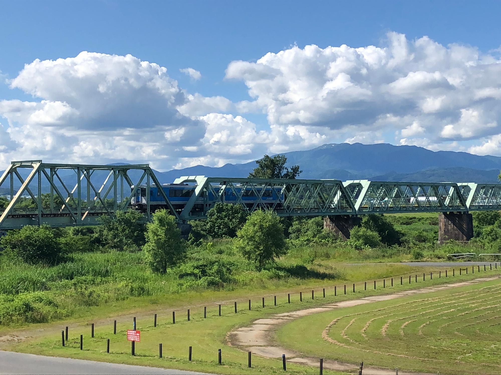 青空の下の最上川橋梁。水色の左沢線車両が通っている
